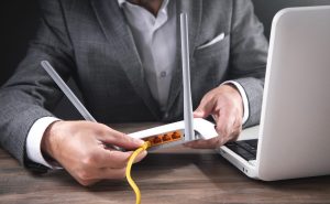 man plugging internet cable into wifi router