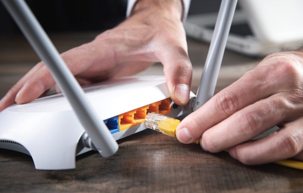 man plugging internet cable to wifi router